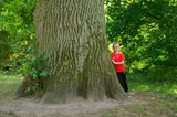 Fototapeta  - chłopiec obok wielkiego pnia drzewa
