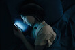A young woman watches social networks on her phone at night or answers a message. The concept of insomnia. Top view.