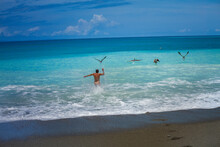Man Bathing In Front Of Pelicans In The Pacific Ocean