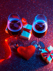 Wall Mural - The concept of Valentine 's Day . Two glasses of champagne on a shiny background. Gift boxes and a red heart