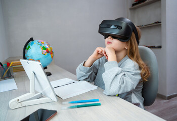 Wall Mural - schoolgirl using vr headset simulators for studying. child is wearing virtual reality glasses sittin