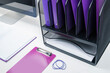 An organized white office desk with purple folders and computer