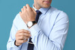 Handsome man in formal clothes adjusting sleeve on color background, closeup