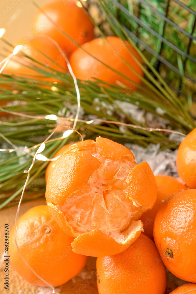 Tasty tangerines with snow and Christmas lights on table