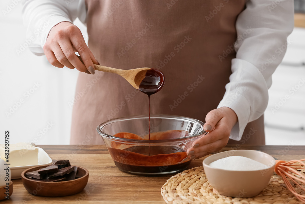 Woman preparing chocolate brownie at kitchen table, closeup