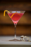 Fototapeta  - Fresh cosmopolitan martini in detail with lemon twist on table with wood background