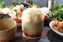 A View Of A Sticky Rice In A Basket Container, Among Other Lao Entrees.