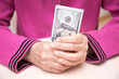 The hands of an elderly woman with dollars close-up. Concept having a financial strategy.