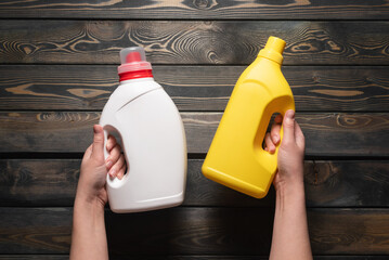 Wall Mural - Two detergent bottles in female hands close up. Top view.