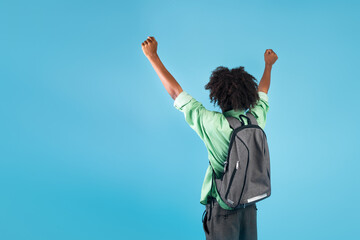 Successful student. African american guy shaking fists, raising arms, standing with backpack over blue background