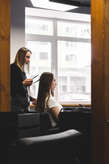 Poster - Master woman hairdresser gently curls hair curling girl in a beauty salon. Hair styling