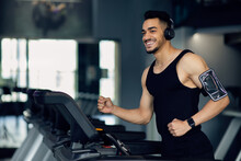 Handsome Muscular Arab Man In Wireless Headphones Jogging On Treadmill At Gym