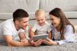 © Prostock-studio - Baby Development Apps. Happy Family With Infant Child Using Digital Tablet Together