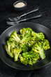 Boiled broccoli with spices in a plate. Black background. Top view