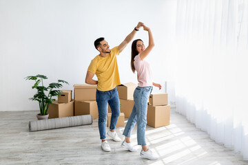 Poster - Affectionate multiracial couple dancing in their house among carton boxes on moving day, free space