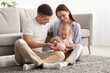 © Prostock-studio - Happy Family With Little Baby Putting Coins In Piggy Bank At Home