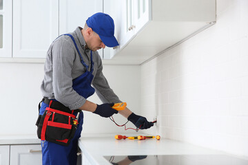 Canvas Print - Professional electrician with tester checking voltage indoors