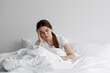 Leinwandbild Motiv Sad european millennial female, worried, suffers from insomnia and headache. Lady sits on bed in bedroom