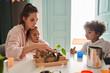 © Yakobchuk Olena - Friendly mother spending time with her kids while sitting at the kitchen at the table