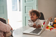 © Yakobchuk Olena - Curly multiracial curious boy touching keyboard of the laptop while sitting at the table