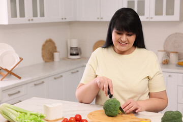 Poster - Beautiful overweight woman preparing healthy meal at table in kitchen