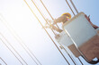 Electrical power line technicians perform maintenance on power lines by using a truck-mounted bucket.