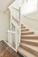 White Staircase With Railing And Pictures On Walls In Stairwell