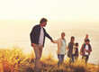 © Mariusz S/peopleimages.com - Say yes to adventure. A multi-generational family walking up a grassy hill together at sunset with the ocean in the background.