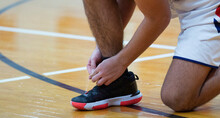 Basketball Player Tyring His Shoes During A Game