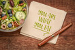 healthy eating and lifestyle concept - you are what to eat reminder words handwritten on a napkin with a bowl of salad