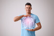 © New Africa - Handsome man holding hands near chest with illustration of lungs on grey background