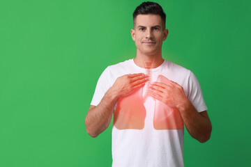 Wall Mural - Handsome man holding hands near chest with illustration of lungs on green background. Space for text