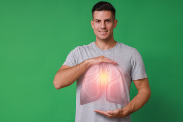 Wall Mural - Handsome man holding hands near chest with illustration of lungs on green background