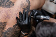 © alones - The tattoo artist creates a picture on the body of a man. close-up of tattoo machines and hands
