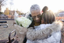 Affectionate Granddaughter Giving Flowers To Grandmother In Park