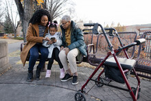 Female Multigenerational Family Using Smart Phone In Autumn Park