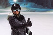 Portret of the woman skier with thumb up as approval or encouragement of the night skiing.Night skiing enjoyment