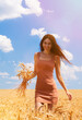 Happy woman enjoy the life in the field. Nature beauty, blue sky, white clouds and field with golden wheat. Outdoor lifestyle. Freedom concept. Woman walk in summer field