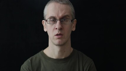 Canvas Print - caucasian man in glasses smokes a cigarette on a black background