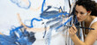 panoramic banner portrait of sexy female artist curly hair woman in white underskirt with brush and palette panting on the artistic studio wall