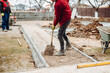 Worker using pavement slabs and shovel to build stone sidewalk. Close up of construction worker installing and laying pavement stones on terrace, road or sidewalk.