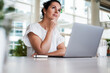 © shellygraphy - thoughtful brooding remote working dark haired woman sitting infront of a laptop or notebook in casual outfit on her work desk in her modern airy bright living room home office with many windows