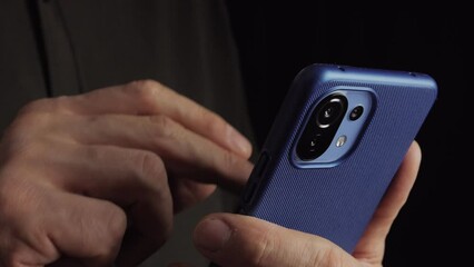 Close-up of a man holding a smartphone in his hands and using an app.