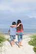 © Milou Dirks - rear view of boy and girl embracing and walking together on beach near ocean in summer