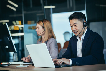 Happy call center employee communicates with customers, advises on video call, remotely, asian business man