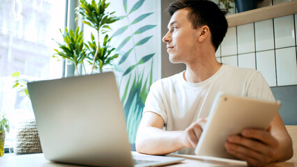 a man uses a laptop in a cafe, writes a message on a social network