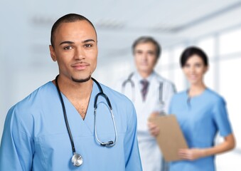 Poster - Portrait of happy young nurse in uniform with healthcare team in background. Successful doctor and nurses