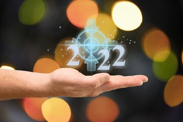 Wall Mural - Businessman holding virtual 2022 number with bokeh background for merry Christmas and happy new year concept.