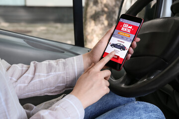 Poster - Woman using mobile phone with open car rent app in automobile, closeup