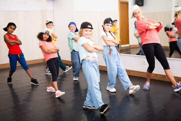 Wall Mural - Cheerful preteen girls and boys hip hop dancers doing dance workout with female trainer during group class..